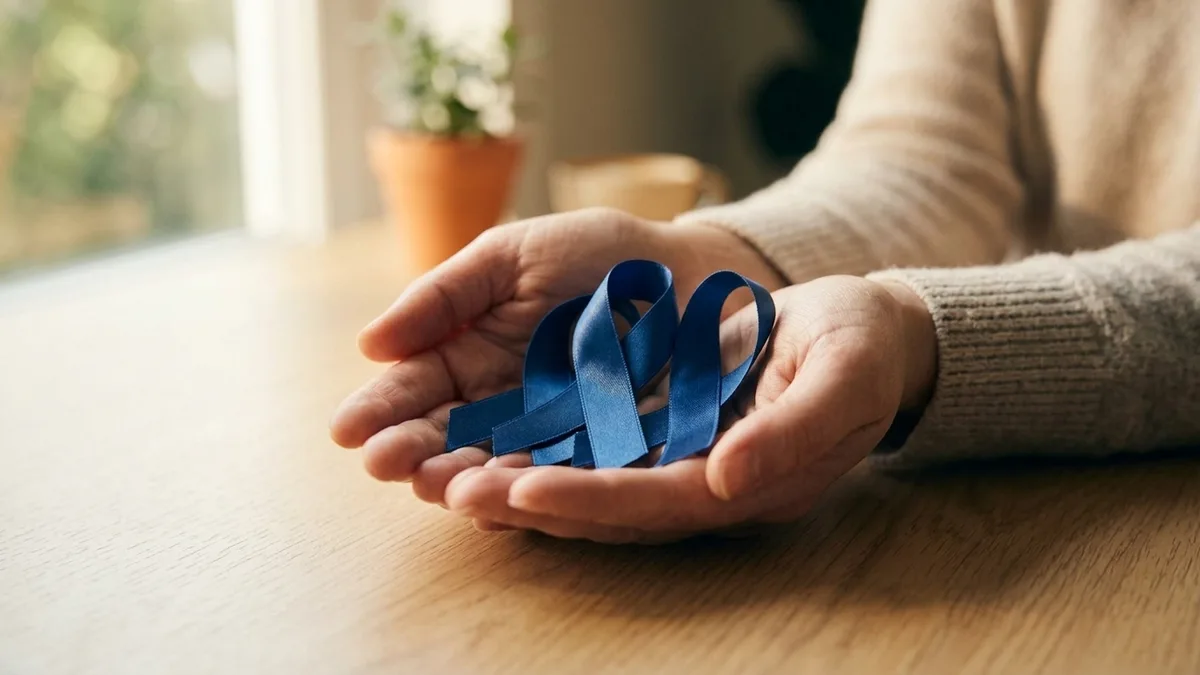 A blue awareness ribbon held between two fingers in soft daylight